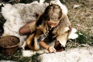 Steinzeit Mädchen auf einem Fell sitzend